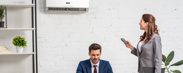 Woman controlling wall mount air conditioning system in a office